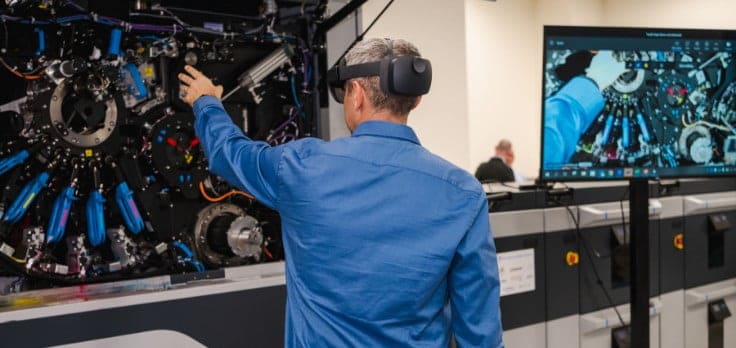 Man wearing HoloLens VR glasses, reaching out to HP Indigo digital press Man wearing HoloLens VR glasses, reaching out to HP Indigo digital press