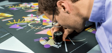 Expert checking the quality of HP Indigo print with a loupe Expert checking the quality of HP Indigo print with a loupe