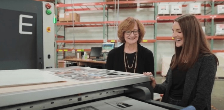 Two women leaning on a large printer Two women leaning on a large printer